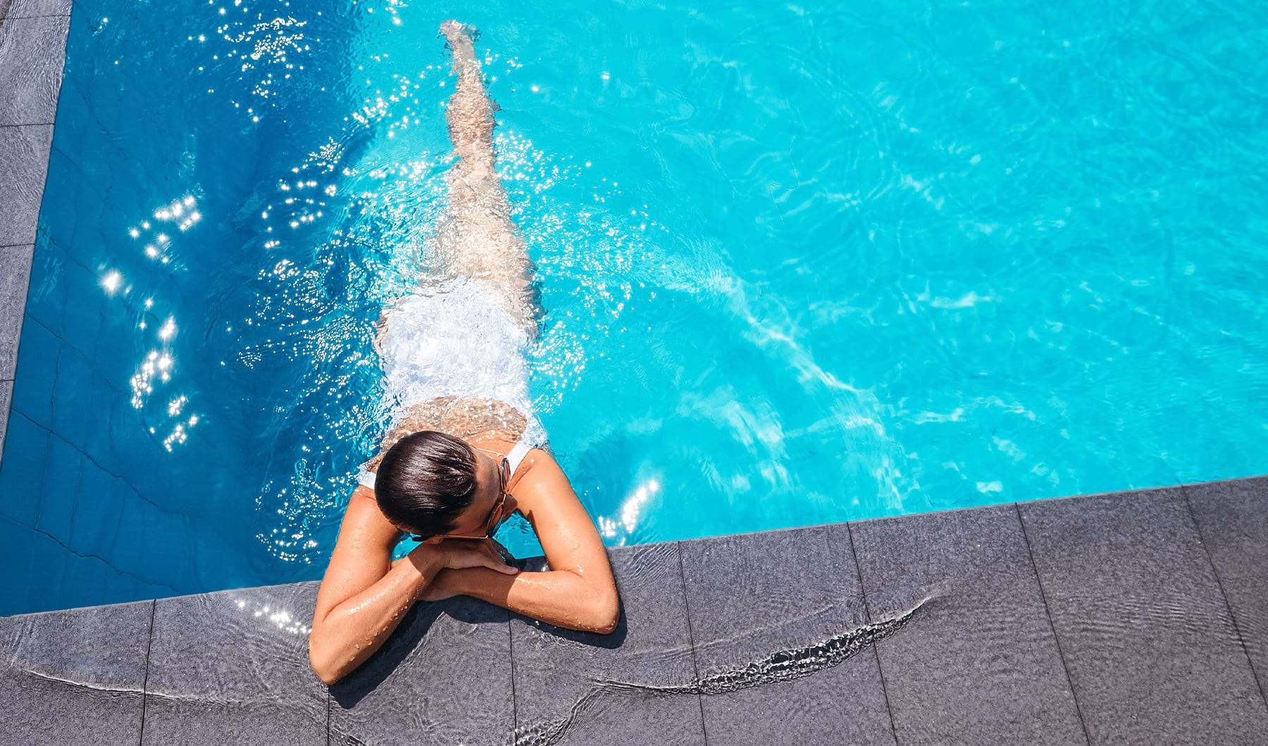 A women is relaxing in a sparkling blue pool 